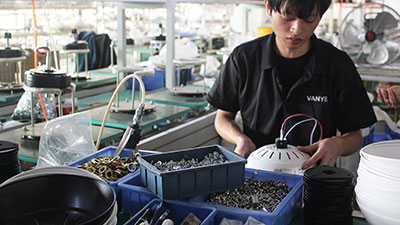 Skilled worker performing detailed ceiling fan component assembly.