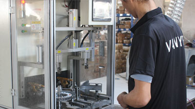 Skilled worker operating machinery for copper wire winding in the ceiling fan motor production line.