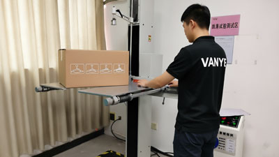 VANYE staff performing drop test on ceiling fan export packaging to ensure safe delivery and durability during transportation.